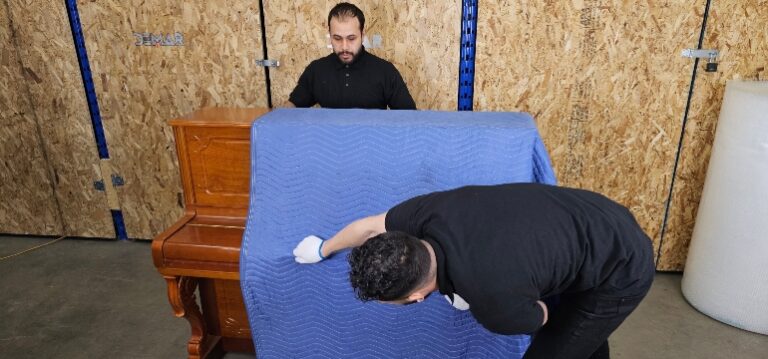Déménageurs Flex protégeant et sanglant un piano dans l'entrepôt